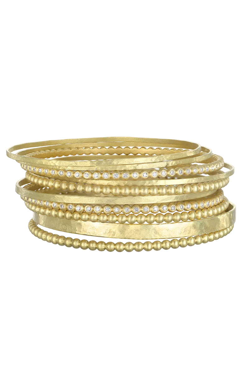 Stack of 14-karat gold bangles with embedded white diamonds on a white background
